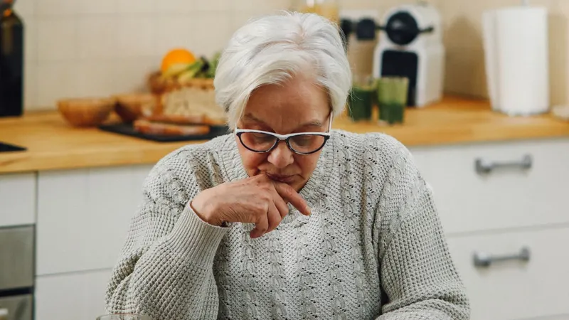 Starsza kobieta zamyślona przy kuchennym stole